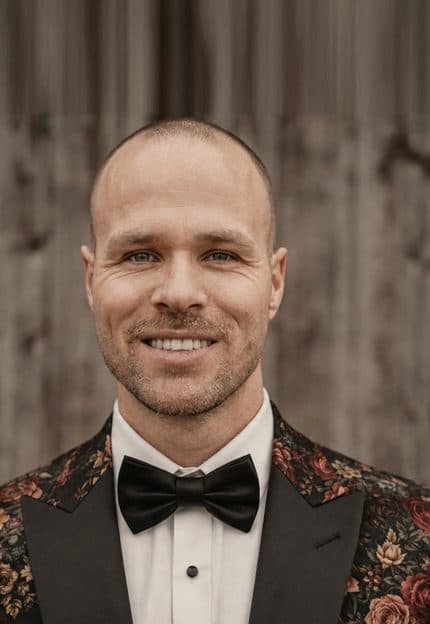 Daniel Hascher lächelt im geblümten Sakko mit Fliege